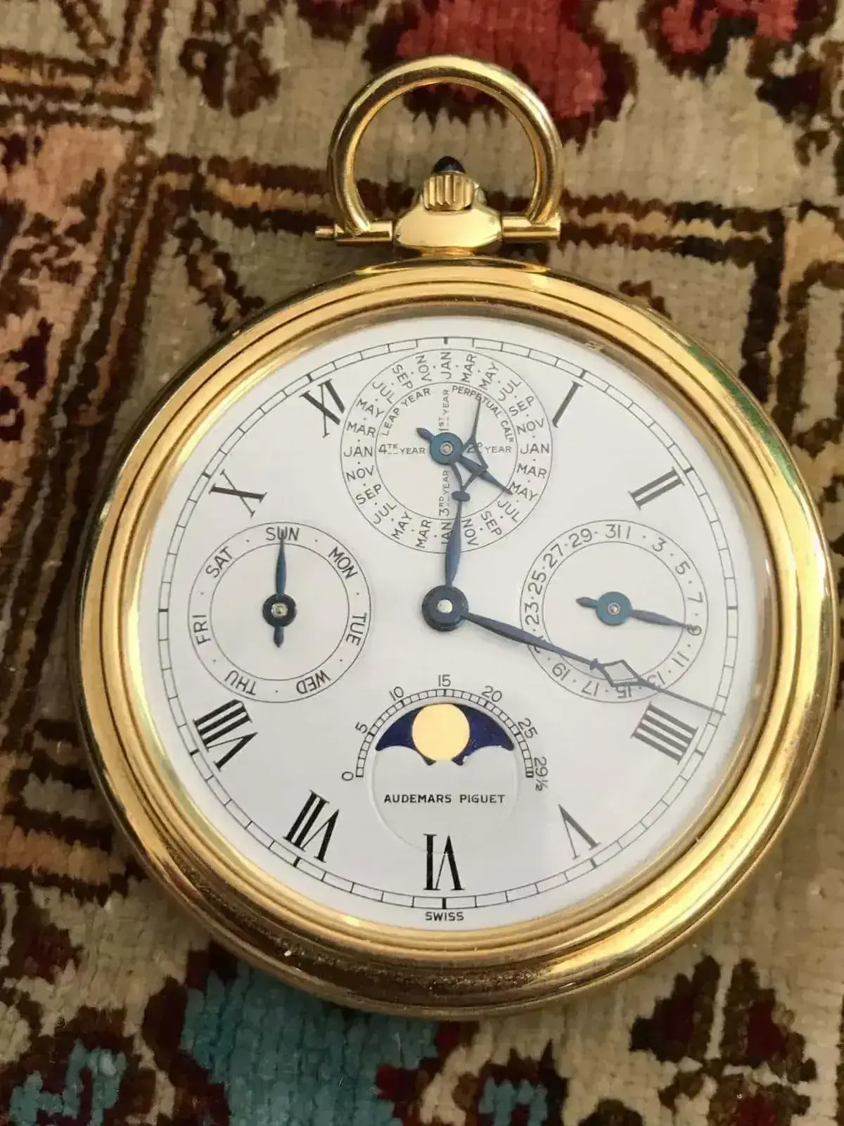 Montre de poche dorée avec cadran complexe.