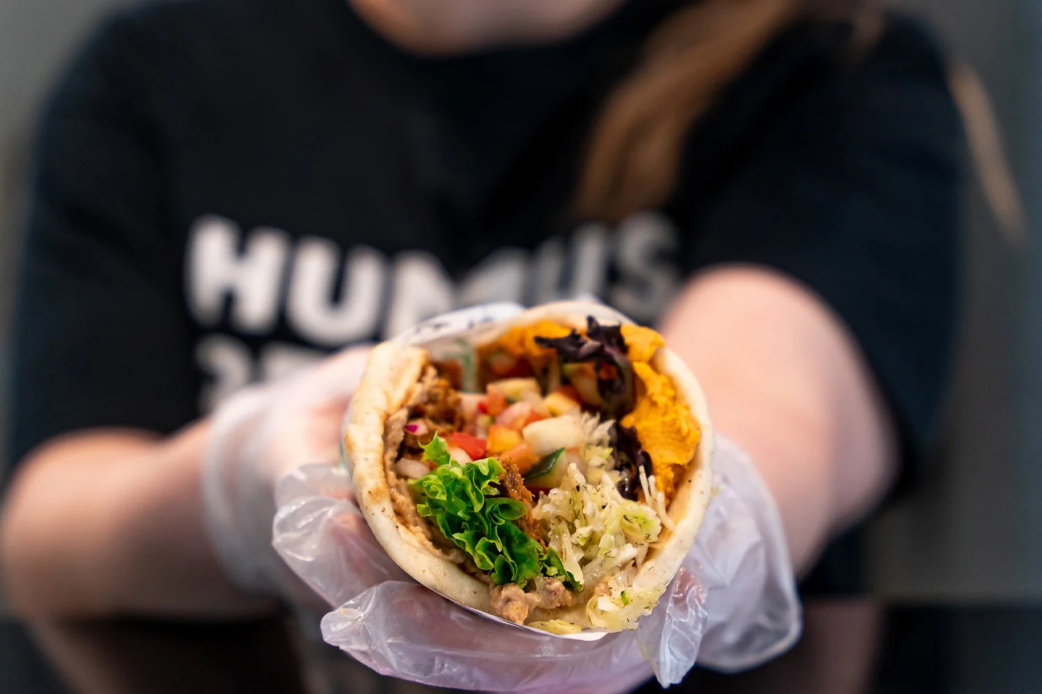 Why a Low-Cost Franchise Is Not the Same as a Cheap One — and How to Tell the Difference A how to hire a manager to run your franchise success setup showing a confident manager overseeing a clean Mediterranean fast-casual counter with fresh hummus bowls and falafel plates at