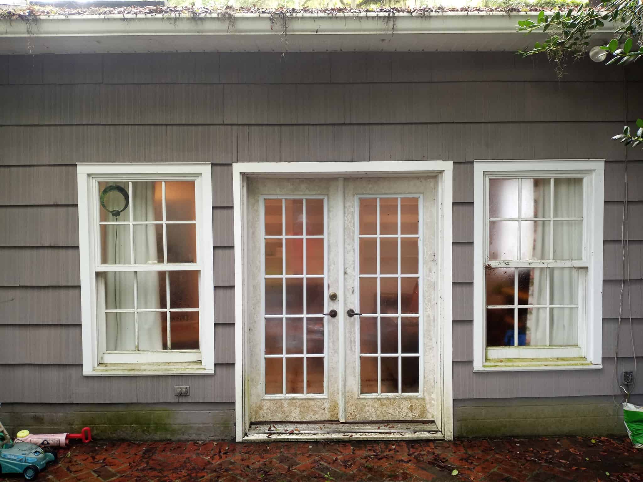 soft wash house cleaning Jacksonville - A professional performing soft wash house cleaning in Jacksonville, spraying water on