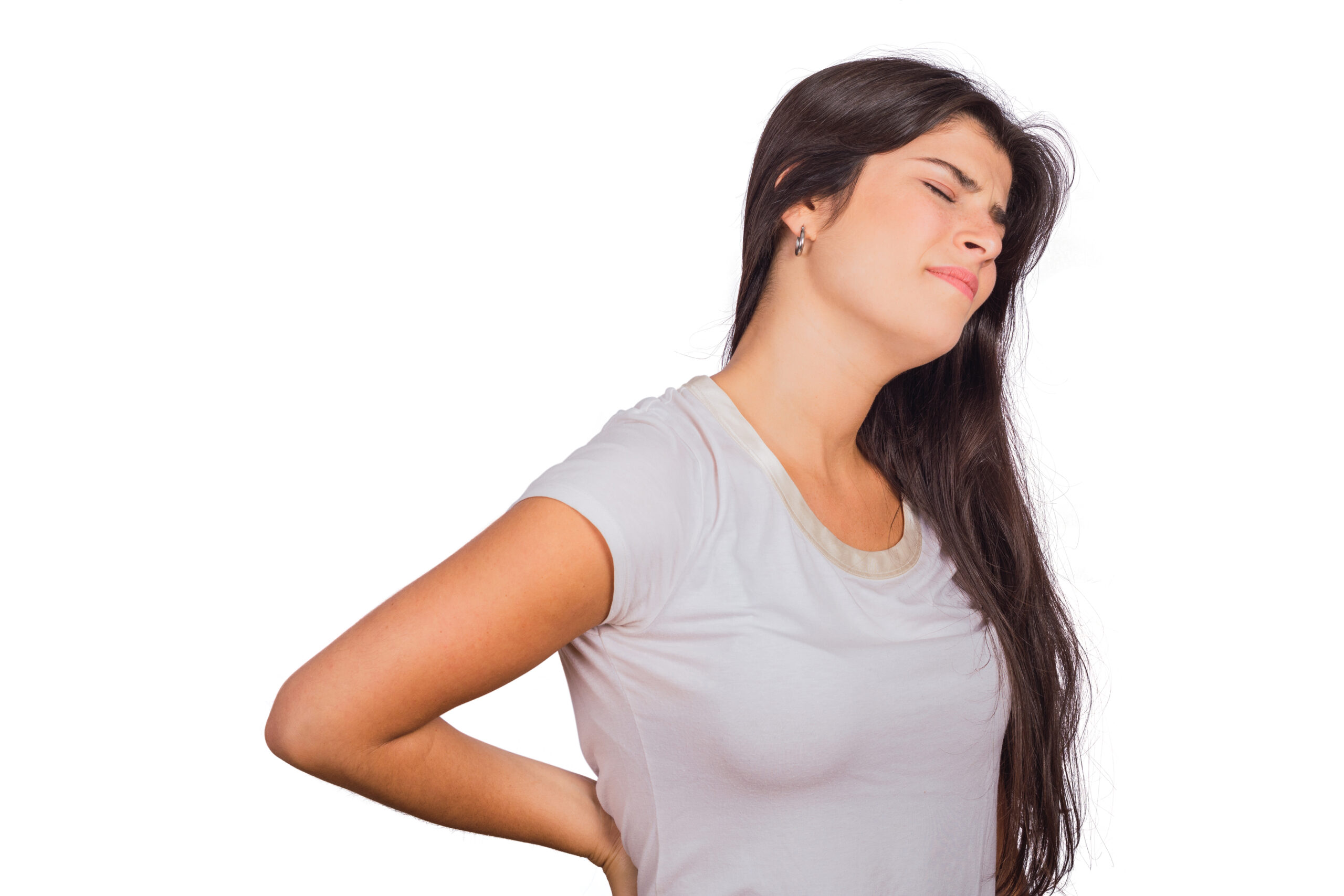 Young woman with lower back pain. Woman in white t-shirt grimacing, clutching her lower back in pain.