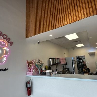 A cozy café interior with modern decor, featuring a counter with boba tea options and seating areas for customers.