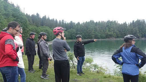 Explore Alaska on Two Wheels: The Ultimate iRide Alaska e-Bike Tour 3 Local guide pointing to a lake while a small group listens.