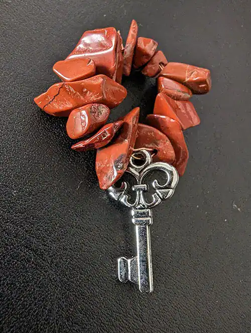 Red jasper naturally-shaped beads on elastic attached to a tiny silver key.
