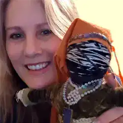 Kellie Jo Close with her art doll designed for relief of financial worry. The doll is dressed in a long dress and an orange long scarf.