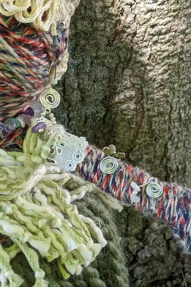Close-up of Leela the health and wellness art dollโs arm bracelet, adorned with fluorite, unakite, and rose quartz stones, from shoulder to wrist.
