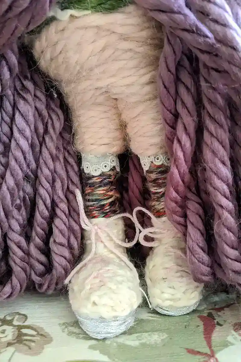 Close-up of Leela the health and wellness art dollโs pink and white tennis shoes, paired with pink "spandex" half leggings beneath her purple skirt.