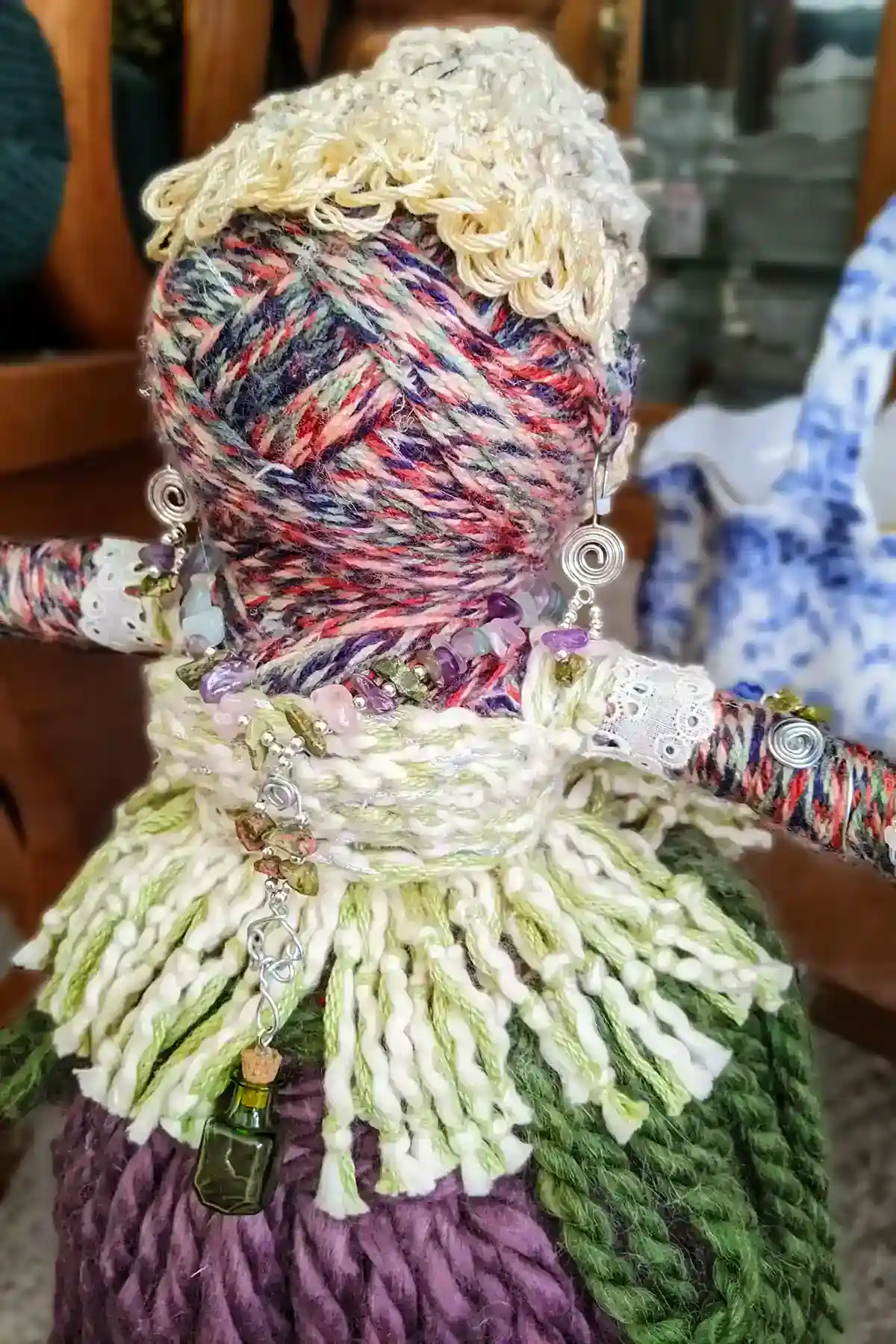 Leela the health and wellness art doll turned slightly to her right, showing gemstone jewelry, spiral earrings, and a small green aromatherapy bottle pendant.