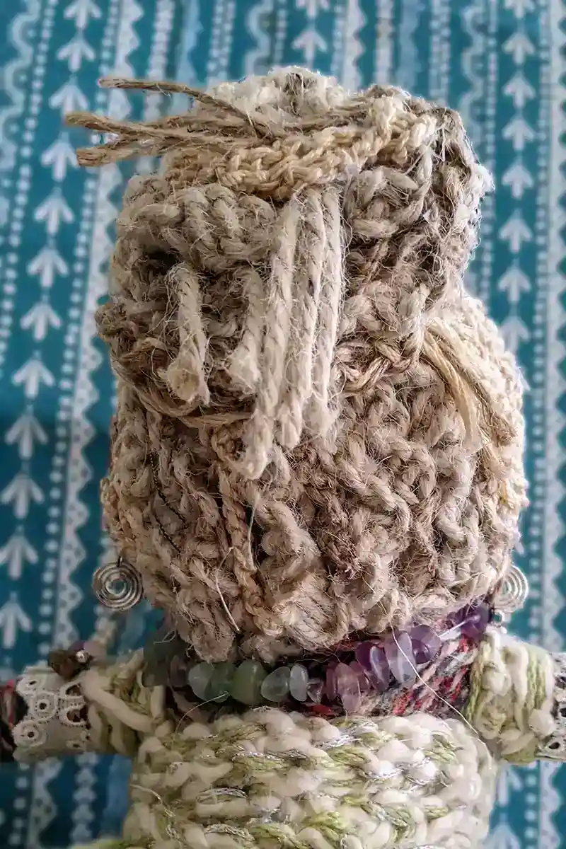 Back view of Leela the health and wellness art doll, showcasing her textured messy bun hairstyle made from yarn.