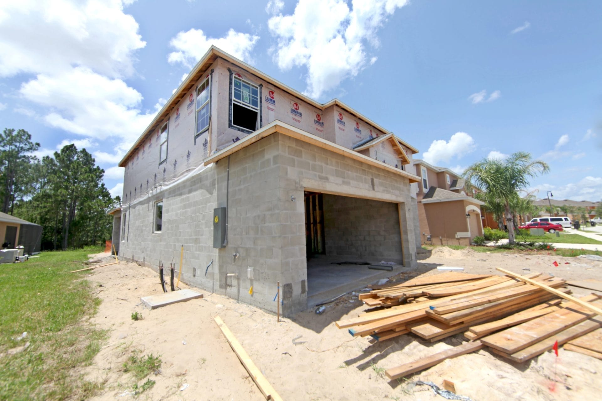 Modern custom home construction Florida with a spacious front yard and palm trees, showcasing contemporary architecture.
