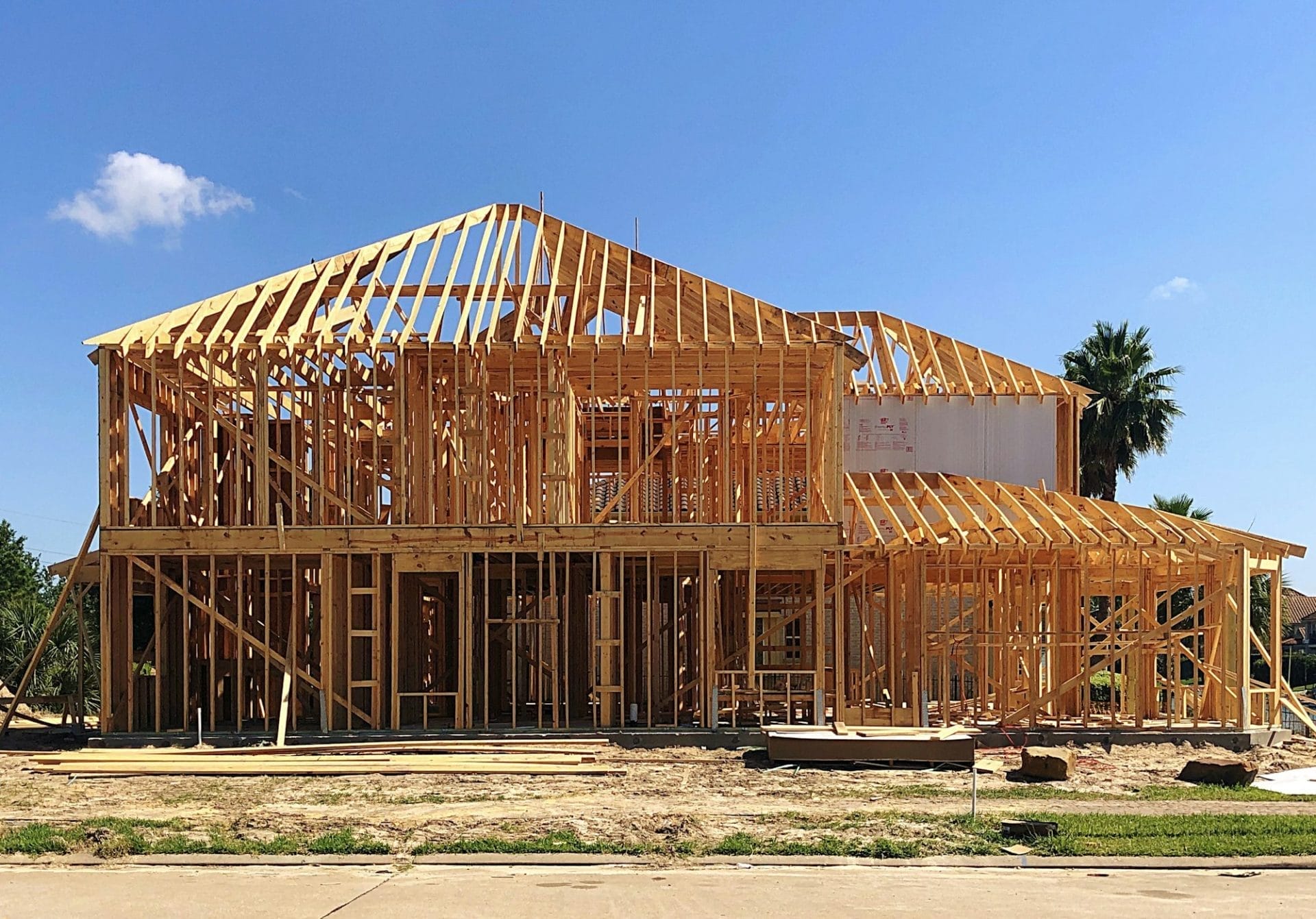 Wooden frame of a house under construction with beams and trusses in place, showcasing the structural framework.