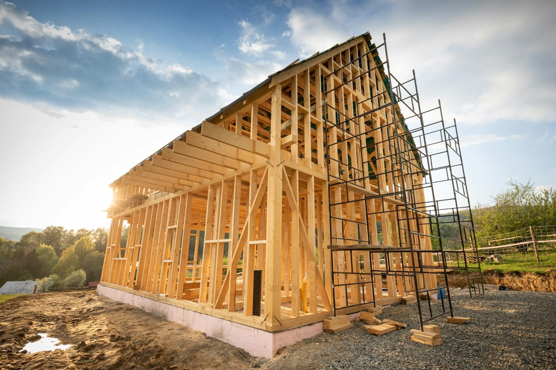 Wooden house frame under construction outdoors, showcasing beams and trusses against a clear sky, part of residential home bu