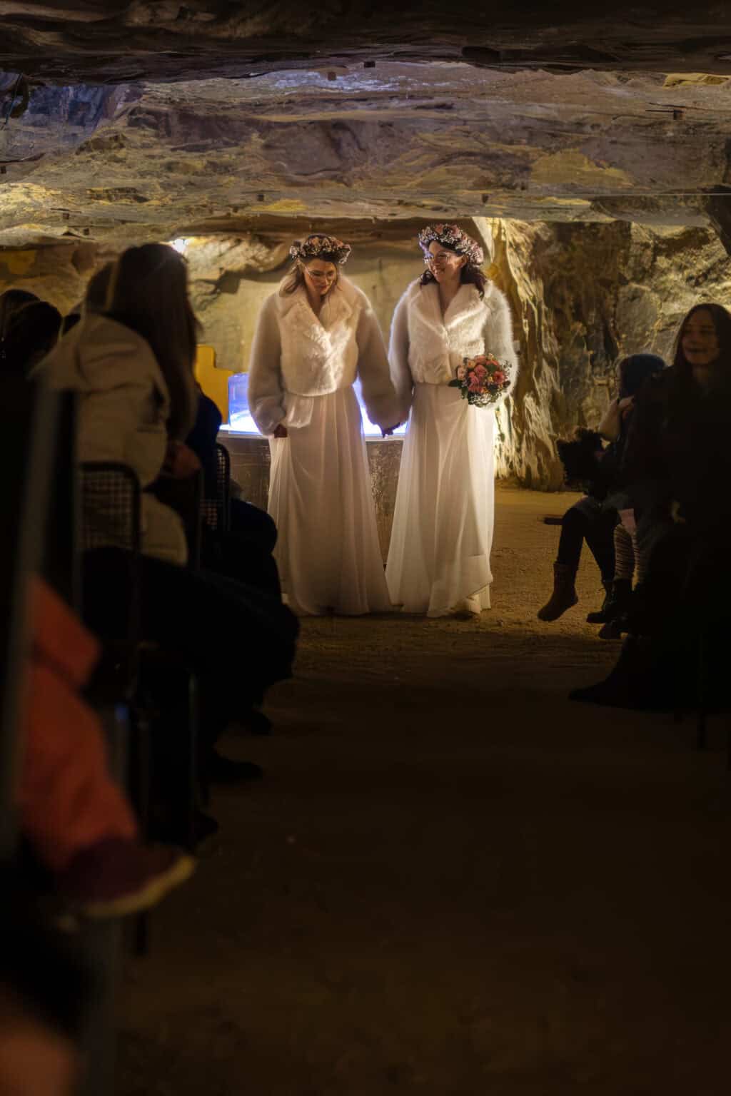 einzug braut Zwei Bräute in weißen Kleidern bei einer Hochzeit in einer Höhle.