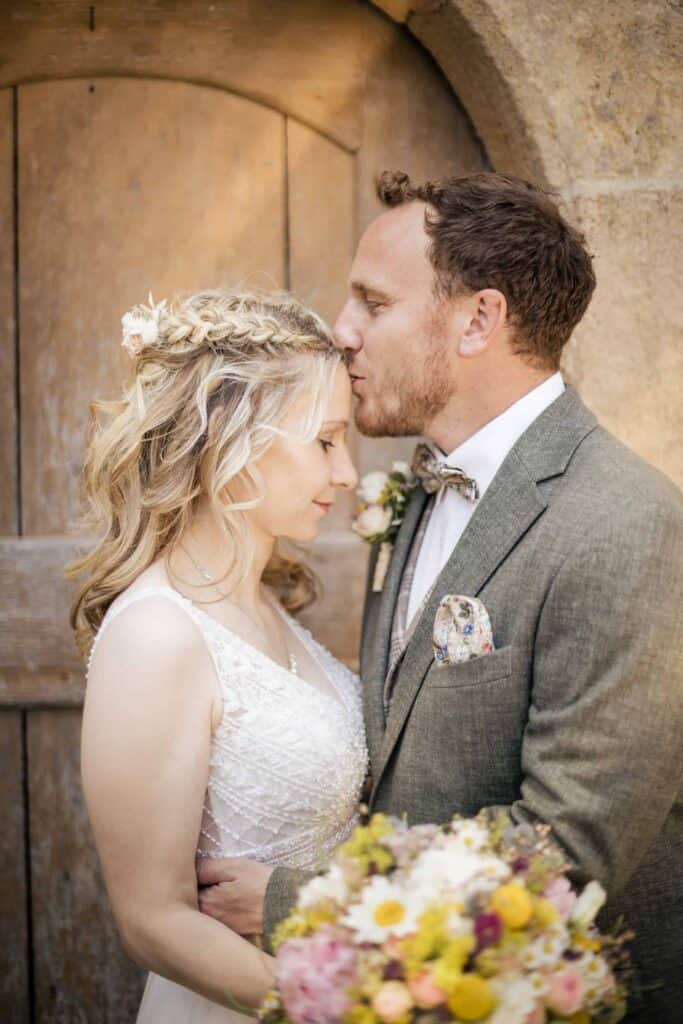 hochzeitsfotograf calw Hochzeitspaar in liebevollem Moment vor einer alten Steinmauer.