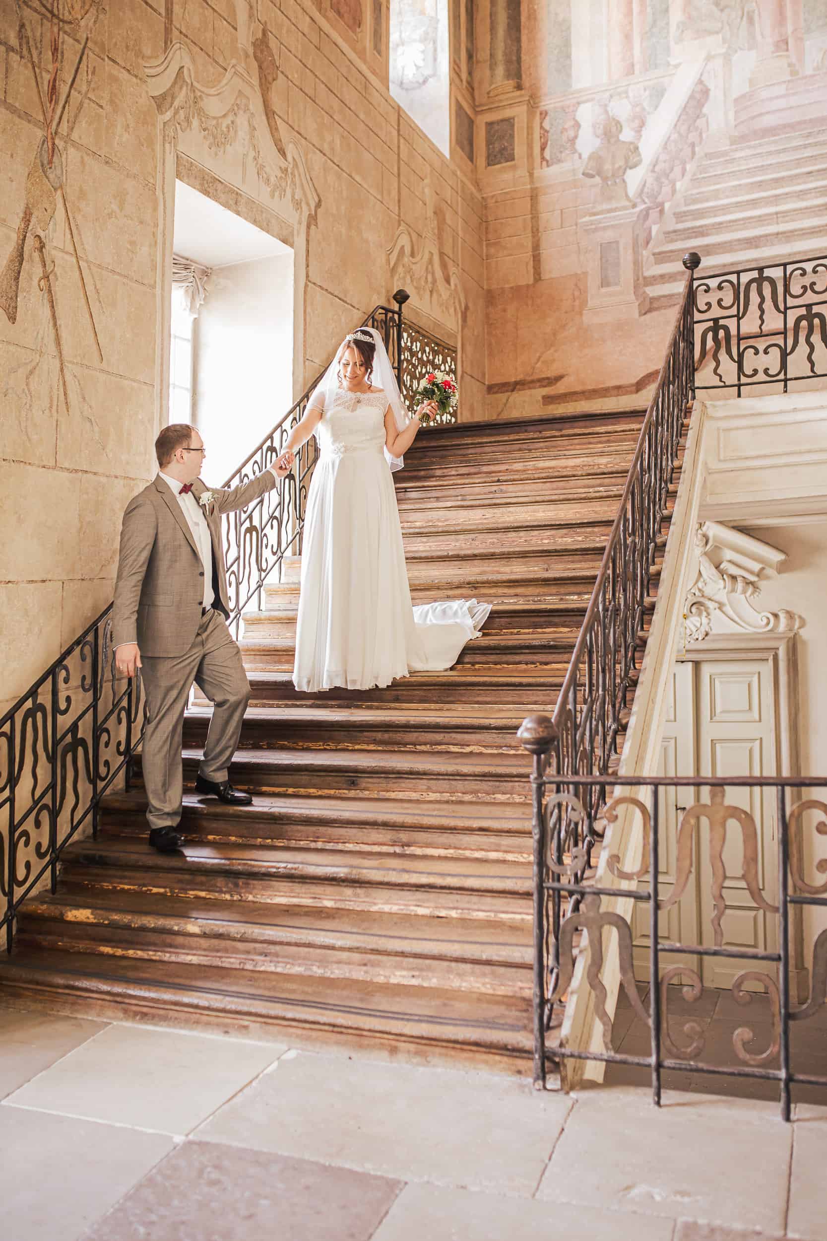 Brautpaar im Schloss Ludwigsburg – romantischer Moment auf der prunkvollen Treppe.