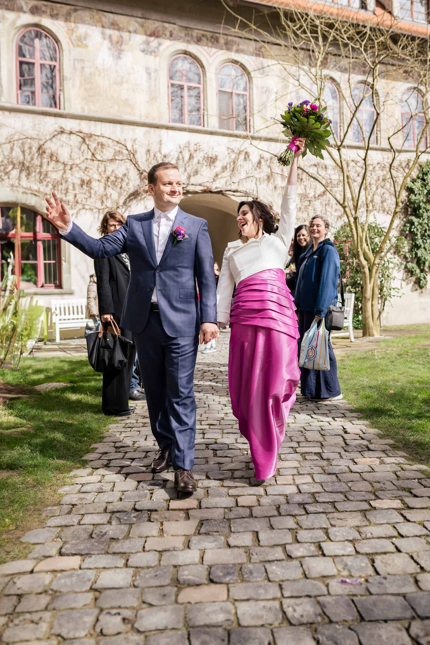 Hochzeitsfotograf Konstanz - Brautpaar bei Hochzeit im Freien, umgeben von Freunden, mit Blumen und historischem Standesamt Gebäude im Hinte.