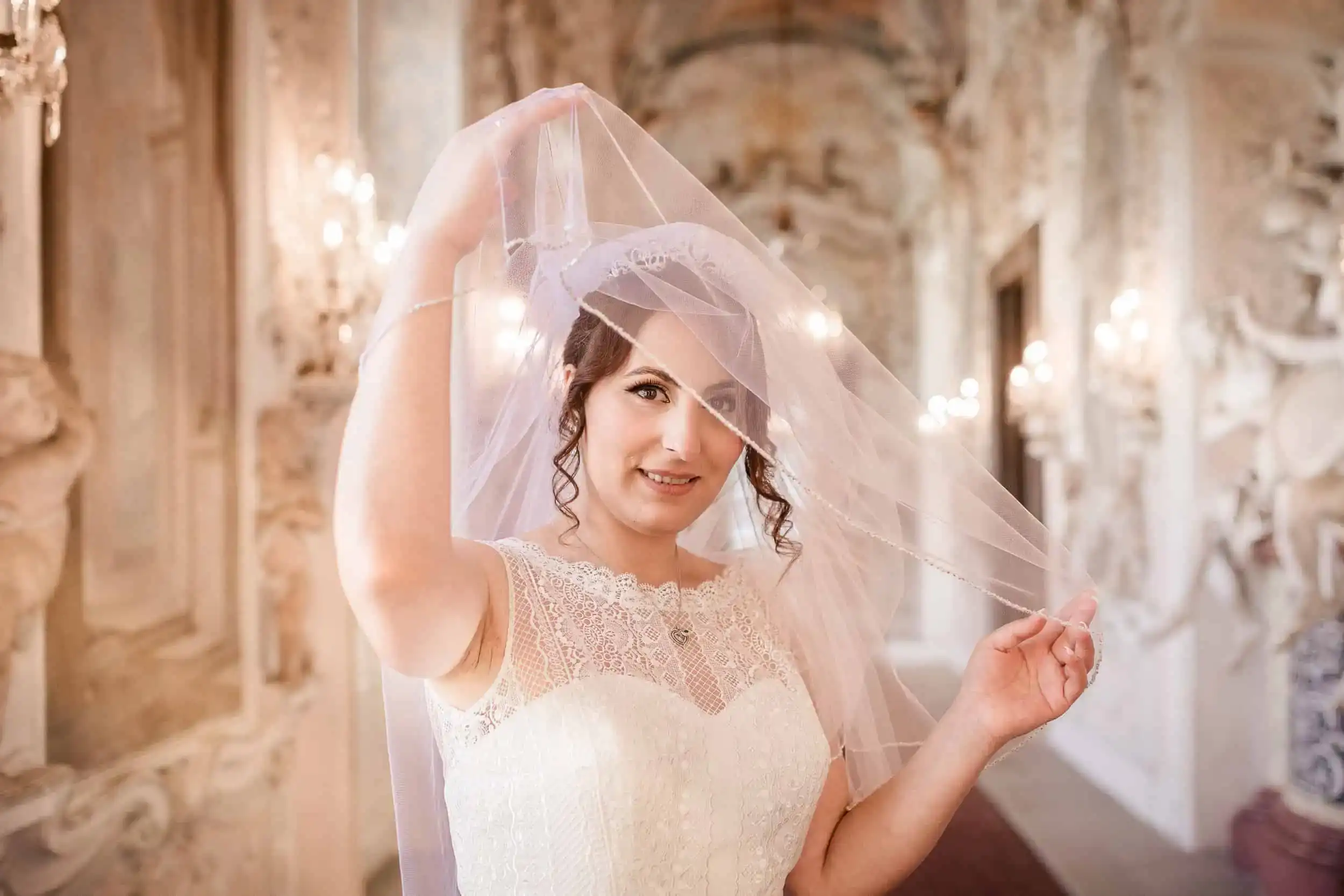 Braut hebt Schleier im barocken Saal bei Hochzeitsfotoshooting