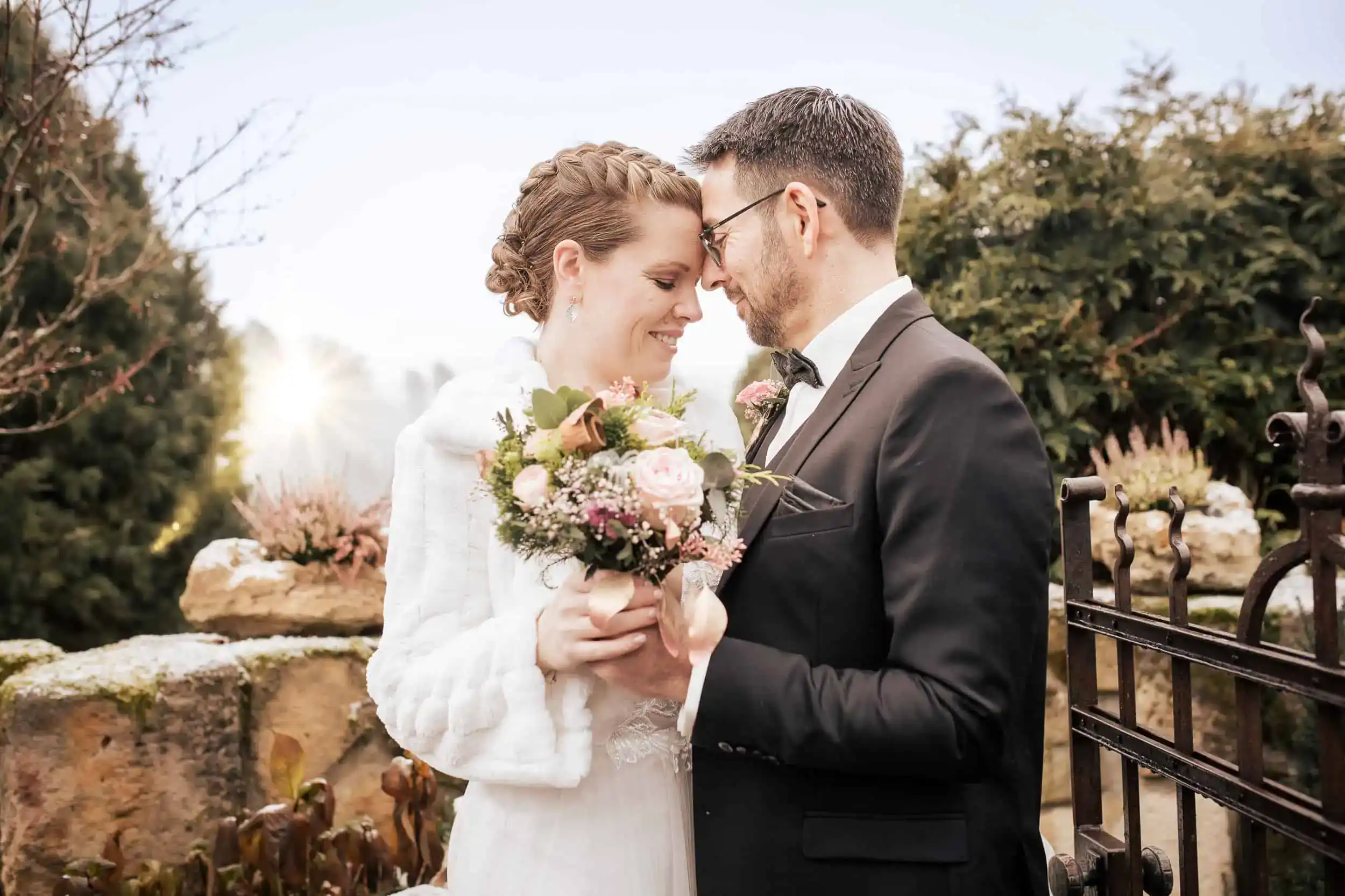 Brautpaar bei Winterhochzeit mit Blumenstrauß und Stirn-an-Stirn Moment