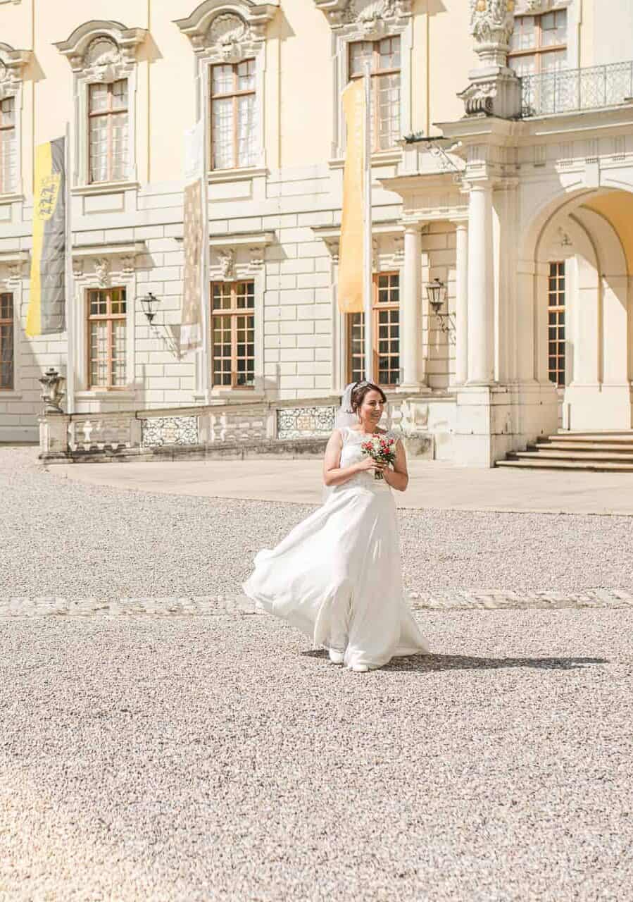 hochzeitsfotograf braut mit brautkeid Braut im Sonnenschein vor Schloss Ludwigsburg – elegante Hochzeitsfotografie in Ludwigsburg.