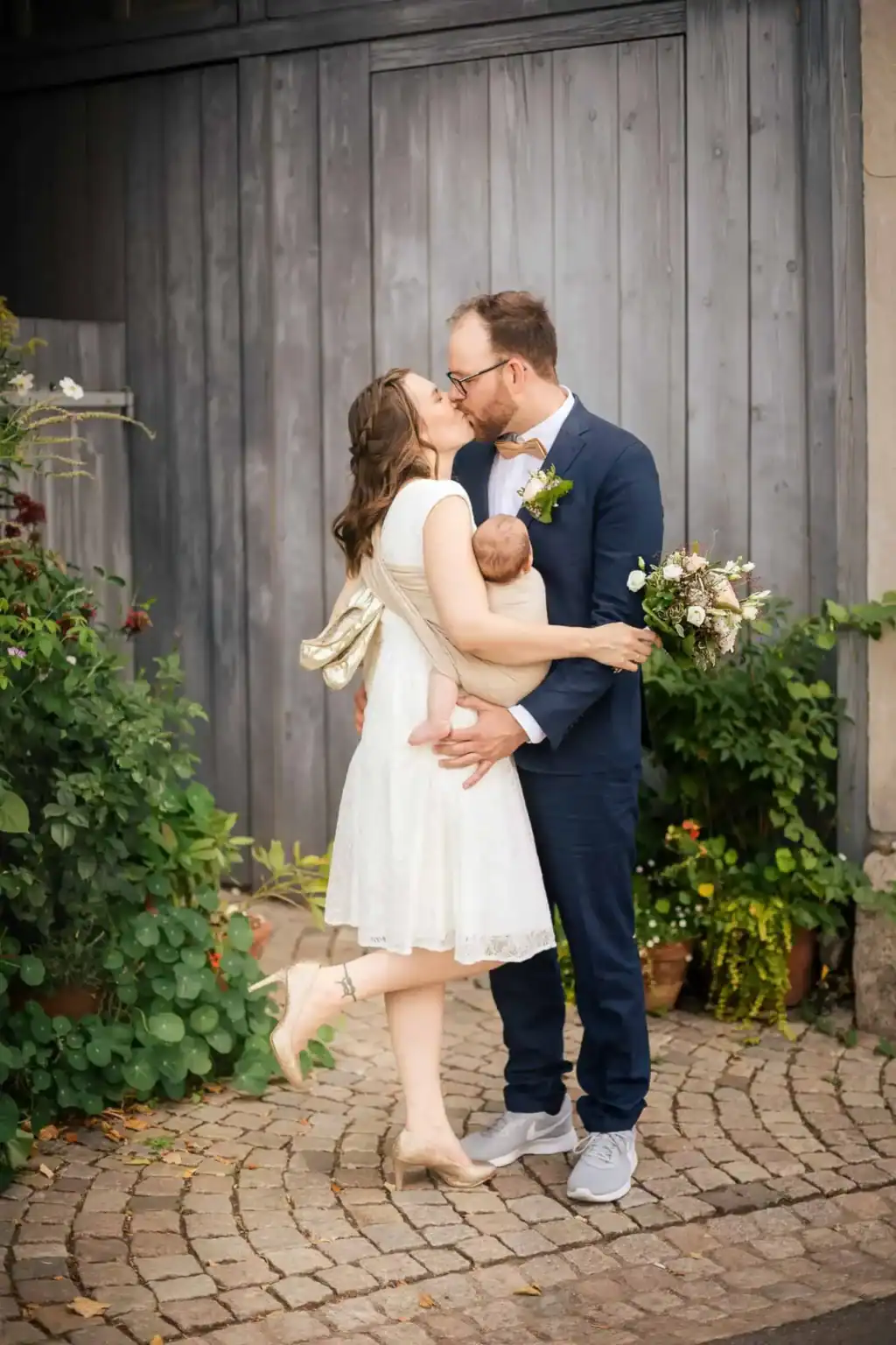hochzeitsfotograf Pforzheim Hochzeitspaar küsst sich mit Baby im Arm bei Sommerhochzeit in Pforzheim