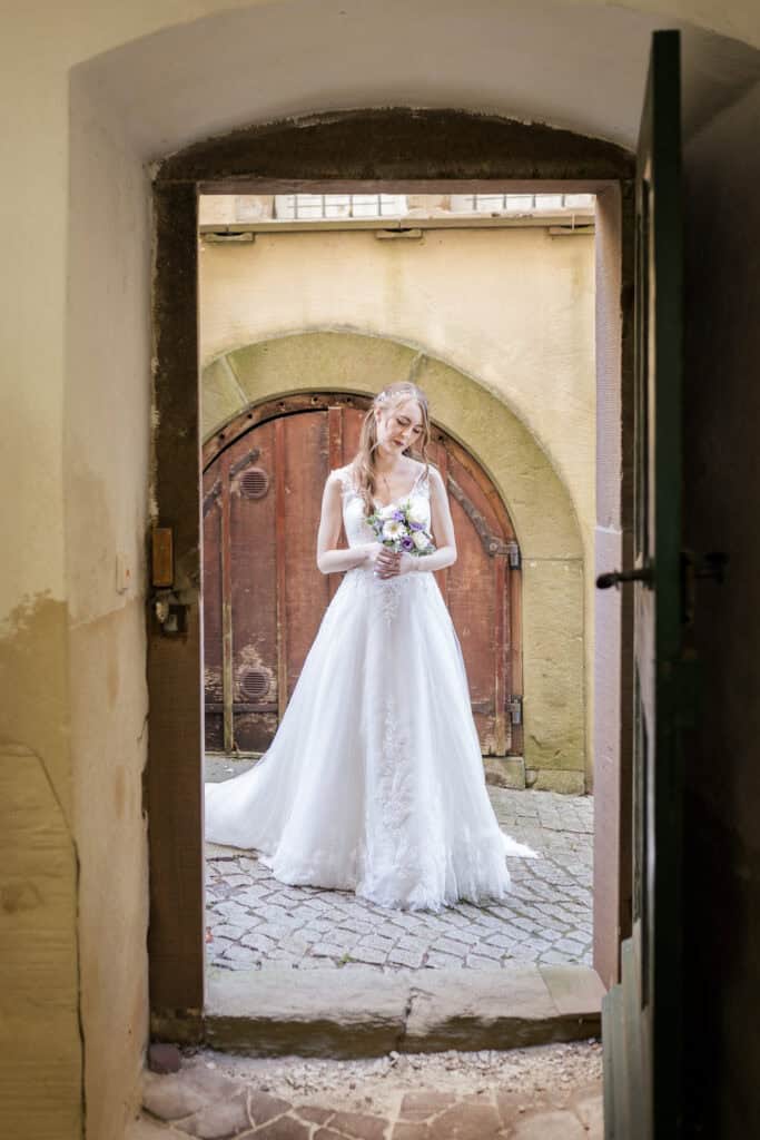 kleine Hochzeit mit Fotograf Böblingen Empfehlung - Braut steht mit Blumenstrauß im Torbogen