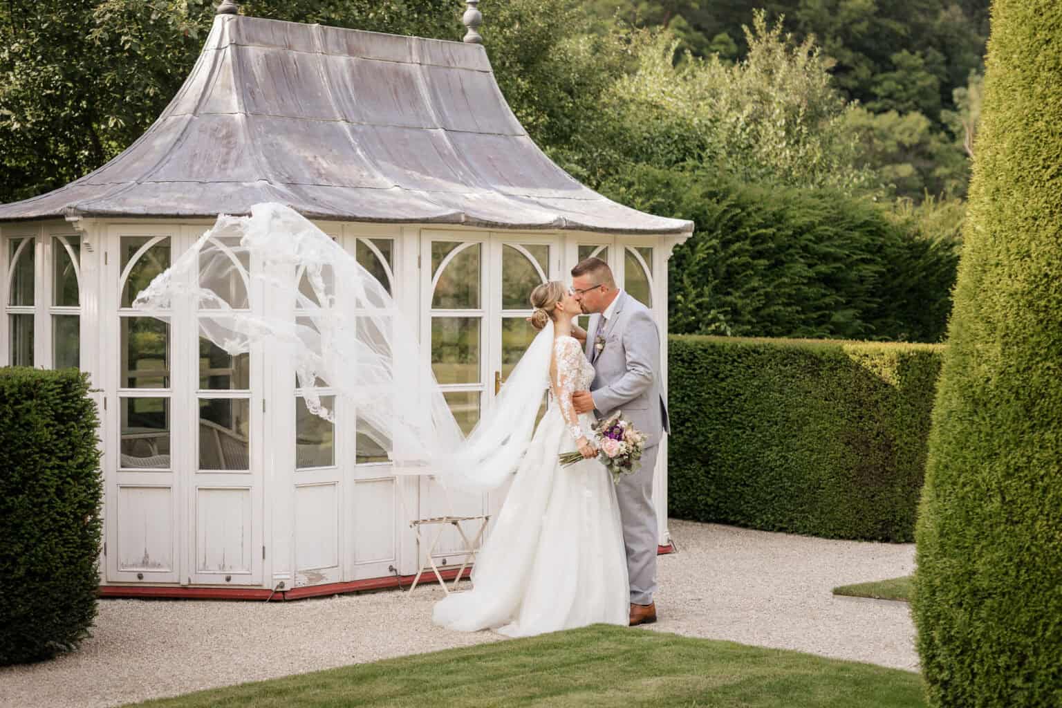 Hochzeitsfotograf Stuttgart Hochzeitspaar vor einem weißen Pavillon im Garten, romantische Atmosphäre, Natur und Liebe.