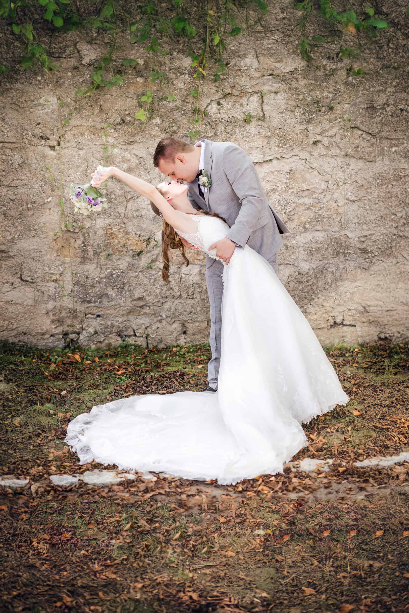 Hochzeitspaar beim Kuss, verliebtes Brautpaar in edlen Outfits bei Fotoshooting.