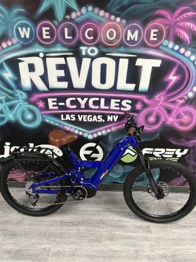 CC Ultra Blue e-bike with brown seat, before a neon "Revolt E-Cycles Las Vegas" mural.