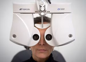 Designer Eyeglasses Portland: Where to Buy Luxury Frames & Prescription Glasses 1 Close-up: Woman's face undergoing an eye exam using a white Topcon machine.
