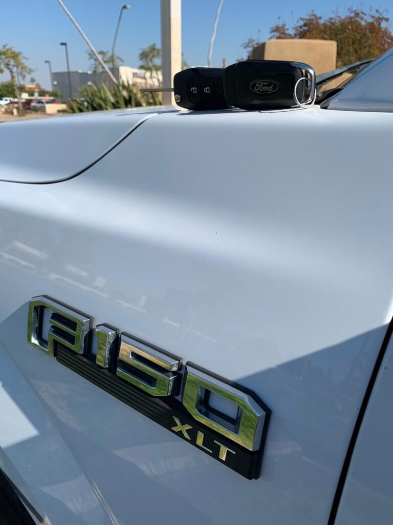 Do Burglars Actually Pick Locks? The Truth Might Surprise You A car key fob resting on the hood of a white Ford F-150 XLT truck outdoors.