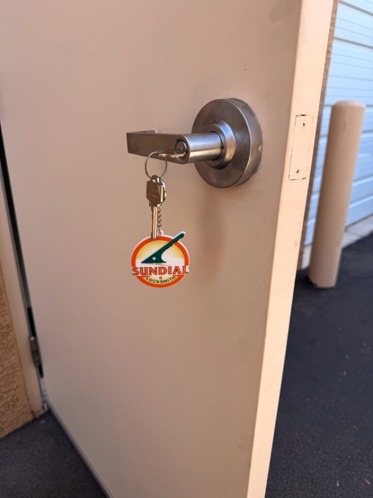 Proximity Key Not Detected? What's Actually Going On With Your Car A set of keys with a Sundial Locksmith branded keychain inserted into a cylindrical deadbolt lock on a white metal storage unit door.