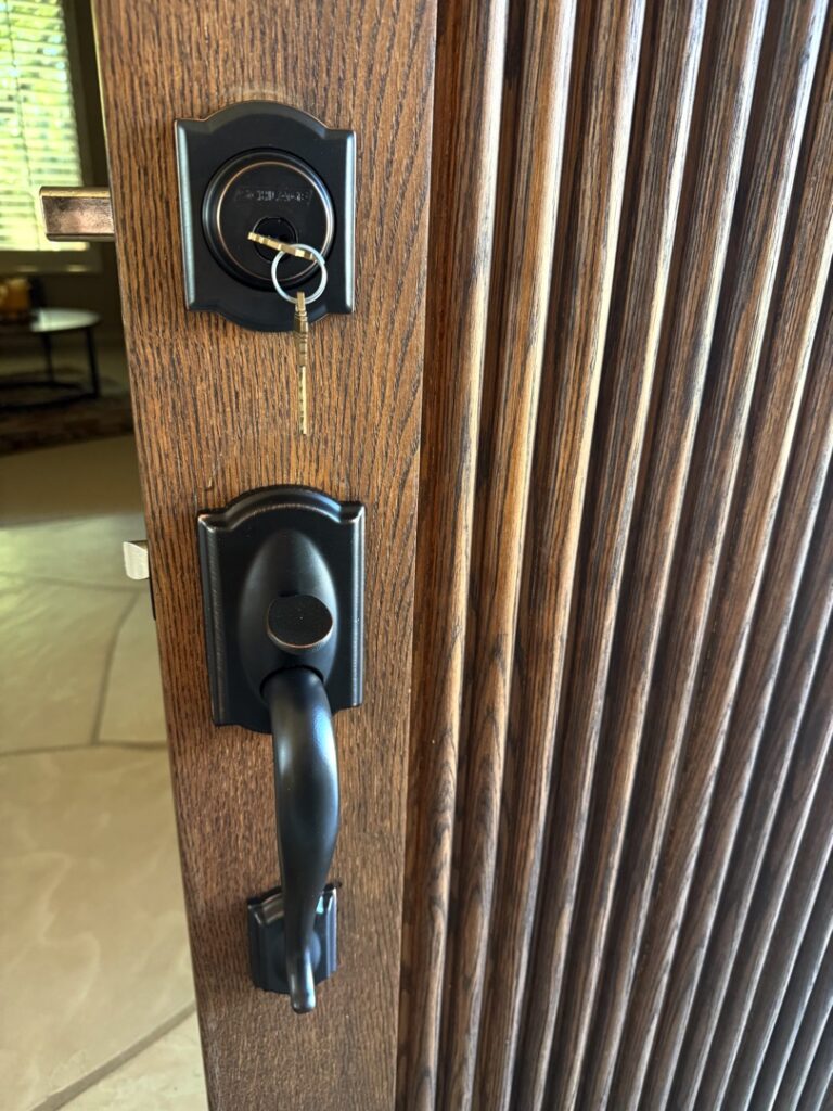 Key Inserted in Front Door Deadbolt Lock A bronze oil-rubbed deadbolt and door handle set with a key inserted into the keyhole on a wooden front door.