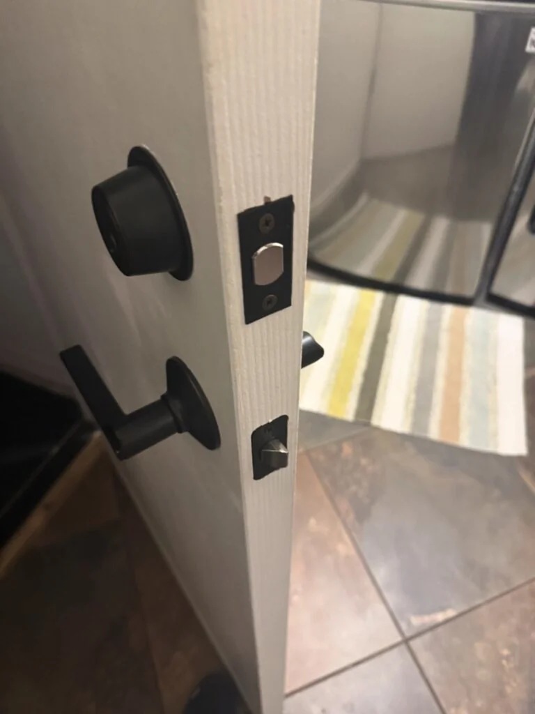 Window Lock Installation: A Small Upgrade with a Big Security Impact Close-up view of a matte black door knob and deadbolt lock installed on a white interior door with strike plates visible on the door frame.