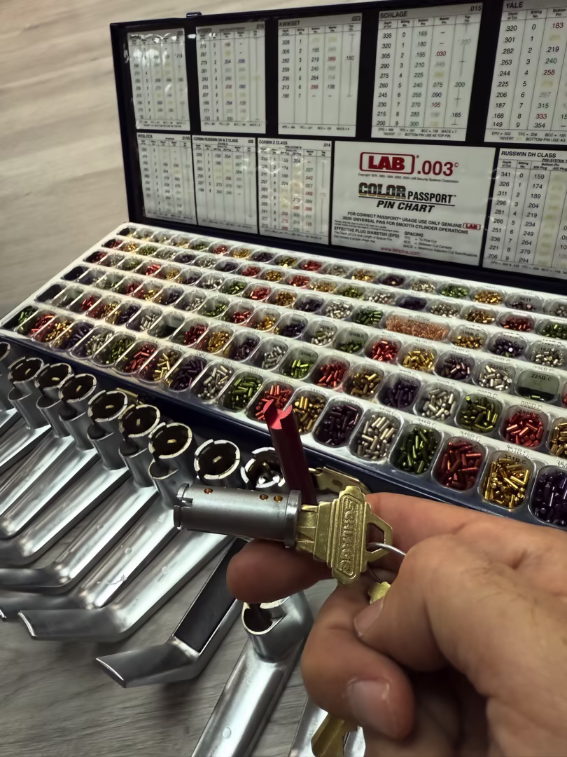 Rekeying a Commercial Building: What's Involved When You Have Dozens of Locks A locksmith technician performing a rekeying commercial building service on a cylinder lock at a Phoenix office building entry door in natural daylight