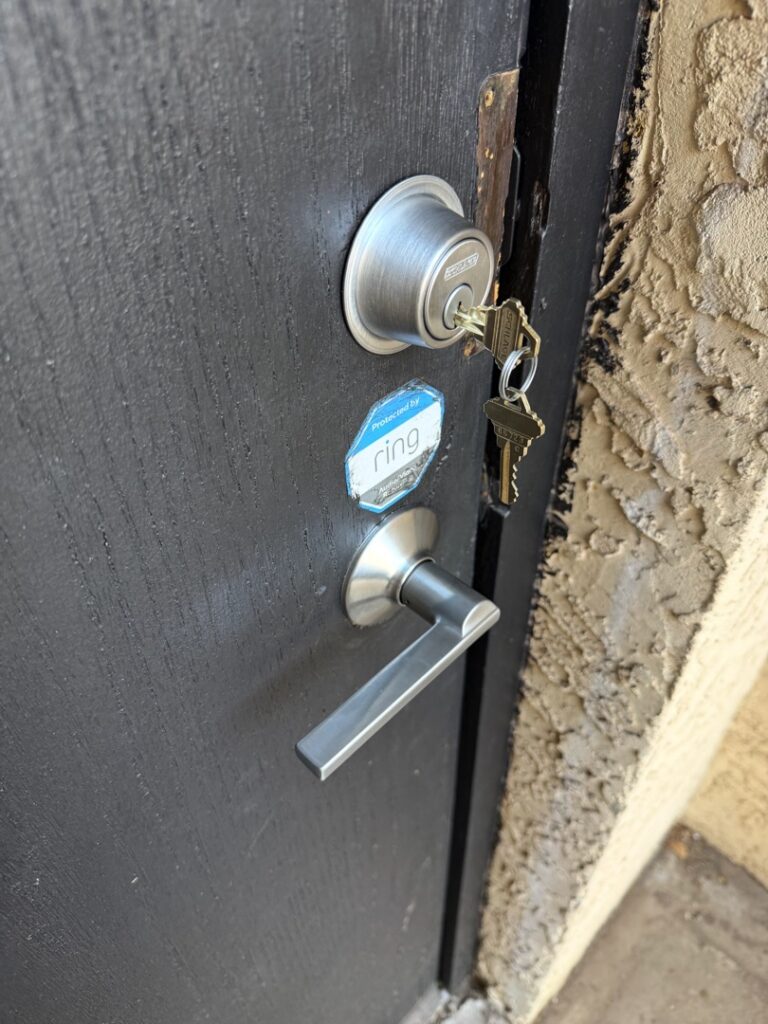 Deadbolt and Handle Lock With Key Inserted A close-up of a residential door showing a silver deadbolt lock with a key inserted and a lever-style door handle on a dark metal door.