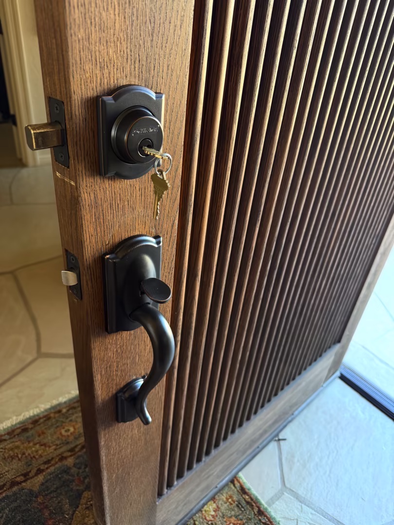 Grade 1 Deadbolt Installation: What It Is and Who Actually Needs One A locksmith performing grade 1 deadbolt installation on a solid wood front door in warm afternoon sunlight in