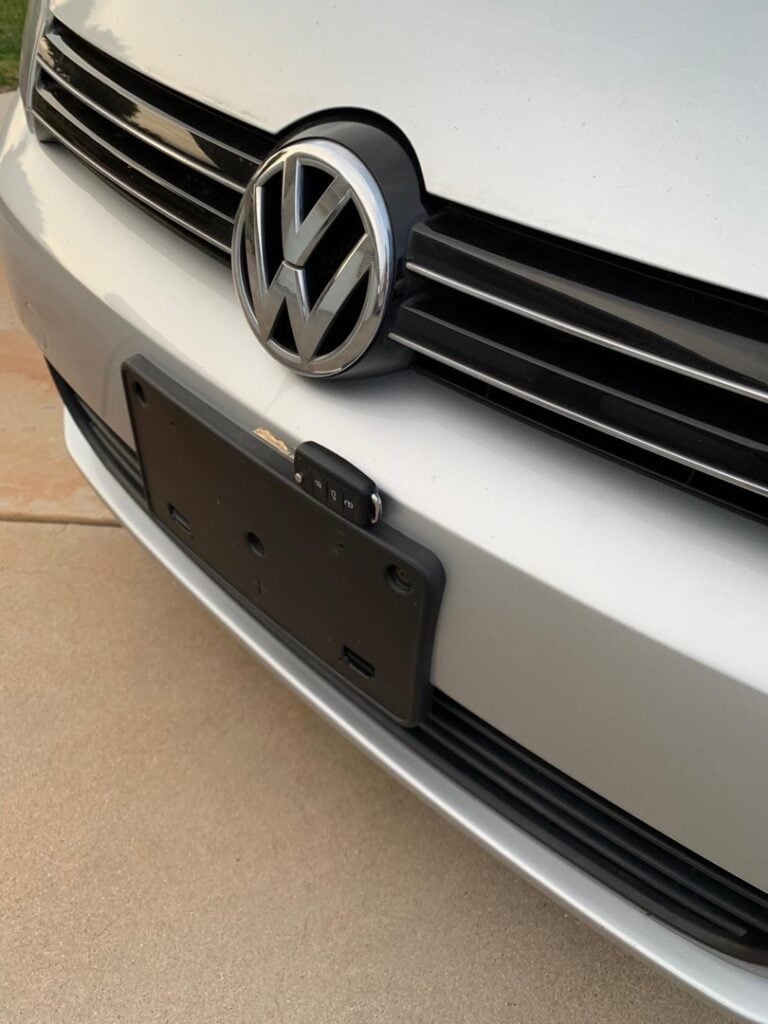 What Makes a Lock 'High Security' — and Is It Worth the Extra Cost? Close-up of a white Volkswagen vehicle's front grille and bumper area featuring a small backup or security camera mounted near the empty license plate holder.