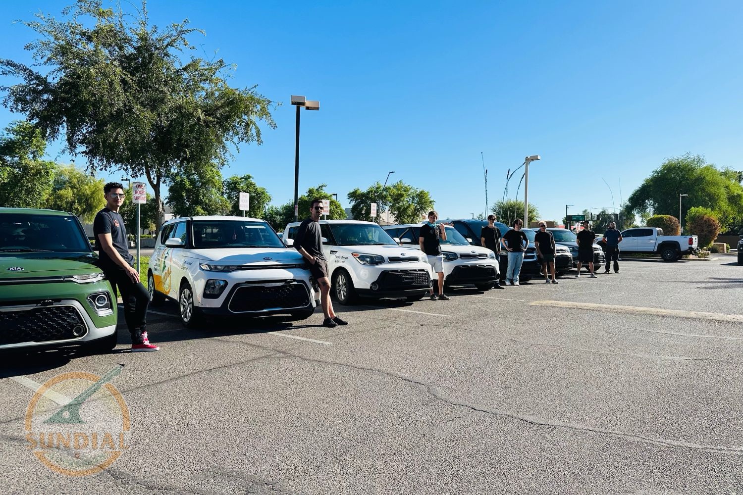 Managing Keys Across a Fleet: What Actually Works A row of Kia Soul vehicles parked in a sunny parking lot with several people standing beside them near trees.