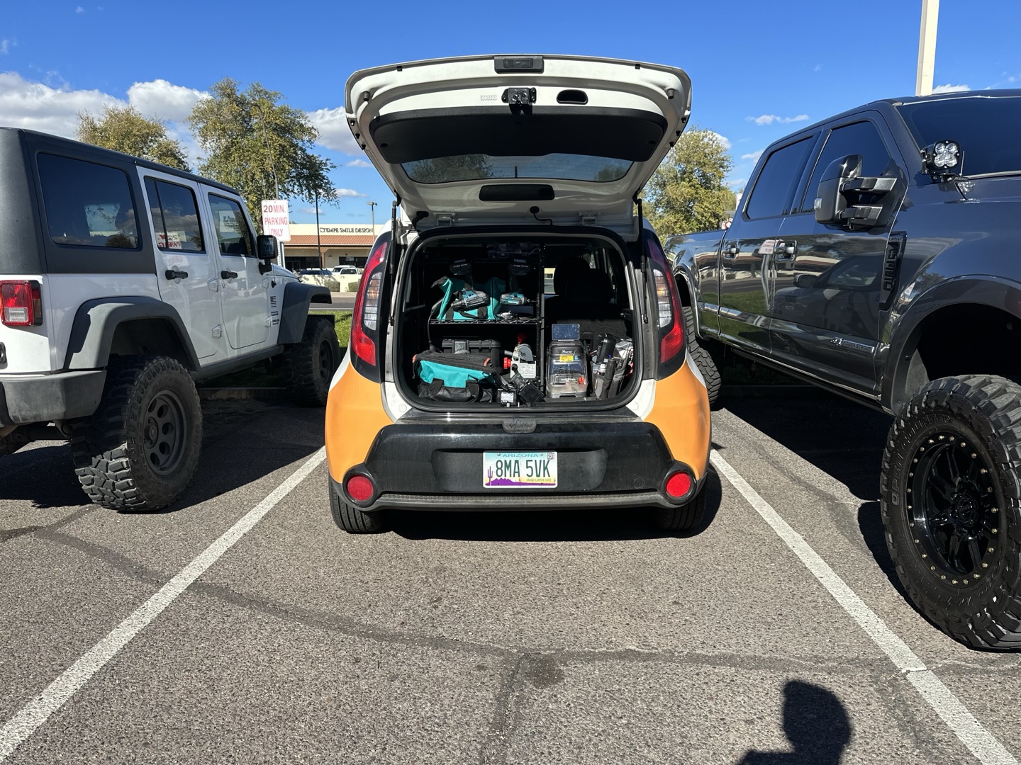 Locksmith for a Warehouse: What's Different About Large Facility Security The open hatchback trunk of a small orange and black car packed with locksmith tools, equipment, and supplies in a parking lot.