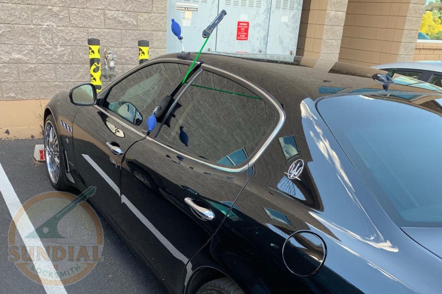What a Slim Jim Is — and Why a Pro Rarely Needs One Anymore A locksmith using a slim jim tool inserted through the window of a black Maserati sedan in a parking lot to unlock the vehicle.