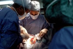 A surgical team in scrubs and masks performing an operation in a well-lit operating room.