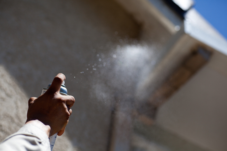 Pest Control Wasp Spray Pest control worker sprays wasp nest on a residential house.