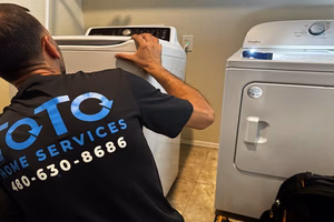 bachelor-party-03 A technician with a TQ Home Services shirt works on a top-loading washing machine next to a dryer in a laundry room.