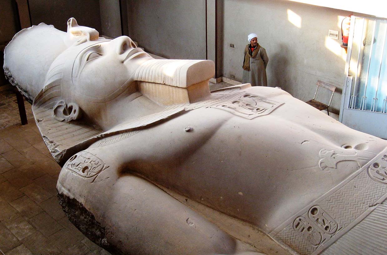 Statue of an ancient Egyptian pharaoh, symbolizing Egypt's rich history, with the Pyramids of Giza in the background.
