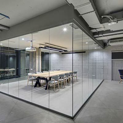 Contemporary office space with full glass partition walls and minimalist meeting area by Westoaks Glass & Mirror.