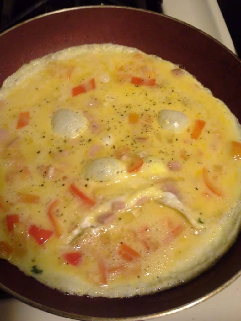 Healthy vegetable scrambled eggs with peppers and onions cooked in a frying pan.