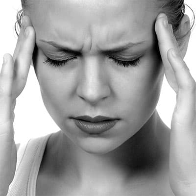 Young woman suffering from headache holding temples.