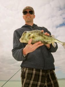 Man holding a fish outdoors for chiropractic health.