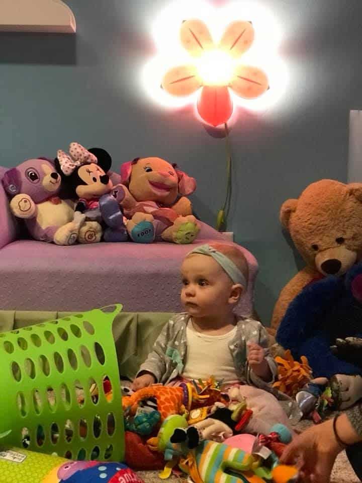 Playroom with stuffed animals, plush toys, and a child surrounded by toys and soft lighting.