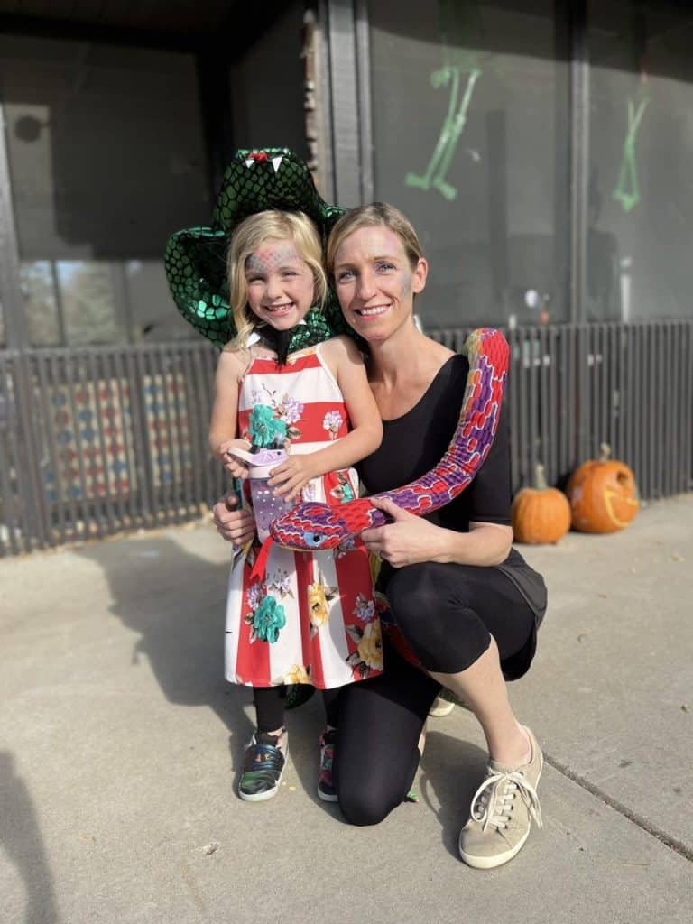 Spooky Halloween fun. Happy little girl with Halloween costume and snake prop.