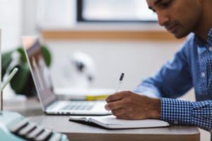 man_doing_research_before_purchasing_a_property_at_a_auction_house - Bridging and Development Finance Solutions Man doing research before purchasing a property at a auction house